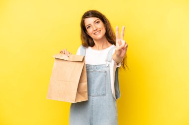 pretty caucasian woman smiling and looking happy, gesturing victory or peace. take away concept
