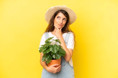 pretty caucasian woman thinking, feeling doubtful and confused. gardering concept