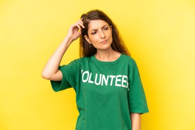 pretty caucasian woman feeling puzzled and confused, scratching head. enviromental volunteer concept