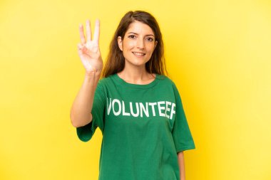 pretty caucasian woman smiling and looking friendly, showing number three. enviromental volunteer concept