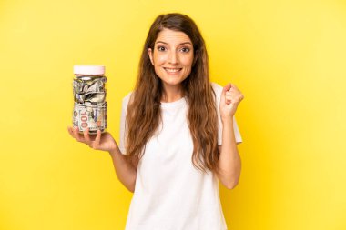 pretty caucasian woman feeling shocked,laughing and celebrating success. dollar banknotes savings