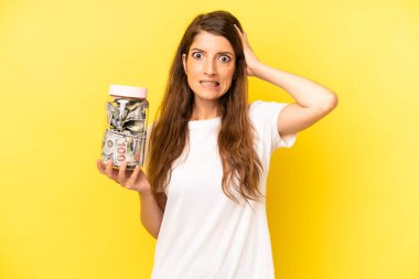pretty caucasian woman feeling stressed, anxious or scared, with hands on head. dollar banknotes savings