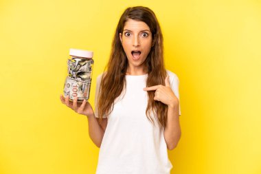 pretty caucasian woman feeling happy and pointing to self with an excited. dollar banknotes savings