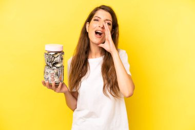 pretty caucasian woman feeling happy,giving a big shout out with hands next to mouth. dollar banknotes savings