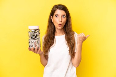 pretty caucasian woman looking astonished in disbelief. dollar banknotes savings