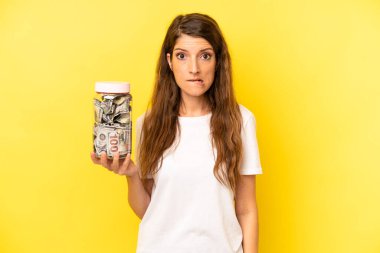 pretty caucasian woman looking puzzled and confused. dollar banknotes savings
