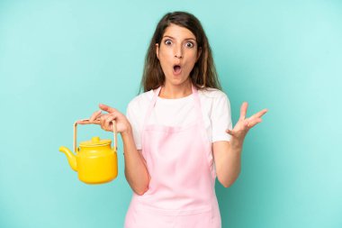 pretty caucasian woman feeling extremely shocked and surprised. housewife with a teapot