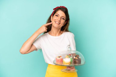 Güzel, beyaz bir kadın kendi gülüşünü işaret ediyor. Ev yapımı kek konsepti