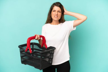 pretty caucasian woman feeling stressed, anxious or scared, with hands on head. empty market basket concept