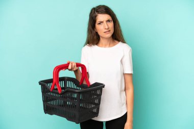 pretty caucasian woman feeling puzzled and confused. empty market basket concept