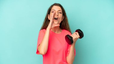 pretty caucasian woman feeling happy,giving a big shout out with hands next to mouth. fitness and dumbbell concept