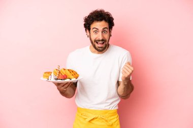 Çılgın sakallı adam şok olmuş hissediyor, gülüyor ve başarıyı kutluyor. Waffle konsepti