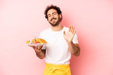 Çılgın sakallı adam mutlu bir şekilde gülümsüyor, el sallıyor, seni selamlıyor ve selamlıyor. Waffle konsepti