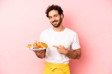 Çılgın sakallı adam neşeyle gülümsüyor, mutlu hissediyor ve bir tarafı işaret ediyor. Waffle konsepti