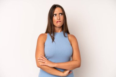 Hispanik güzel kadın şüpheye düşüyor ya da düşünüyor, dudağını ısırıyor ve kendini güvensiz ve gergin hissediyor, kenarda yer arıyor.