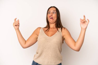 hispanic pretty woman shrugging with a dumb, crazy, confused, puzzled expression, feeling annoyed and clueless