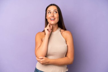 İspanyol güzel kadın mutlu bir şekilde gülümsüyor ve hayal kuruyor ya da şüphe ediyor, yan tarafa bakıyor.