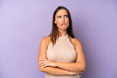 Hispanik güzel kadın şüpheye düşüyor ya da düşünüyor, dudağını ısırıyor ve kendini güvensiz ve gergin hissediyor, kenarda yer arıyor.