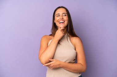 İspanyol güzel bir kadın mutlu, kendinden emin bir ifadeyle gülümsüyor. Elleri çenesinde, merak ediyor ve yan tarafa bakıyor.