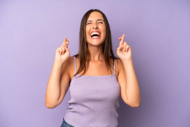 İspanyol güzel kadın gülümsüyor ve endişeyle iki parmağını çapraz yapıyor. Endişeli hissediyor, iyi şanslar diliyor ya da umut ediyor.