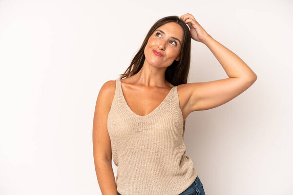 hispanic pretty woman smiling cheerfully and casually, taking hand to head with a positive, happy and confident look