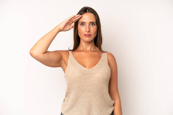hispanic pretty woman greeting the camera with a military salute in an act of honor and patriotism, showing respect