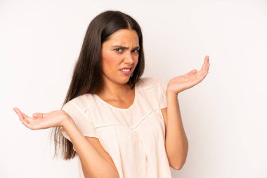 hispanic pretty woman shrugging with a dumb, crazy, confused, puzzled expression, feeling annoyed and clueless