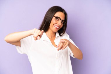 İspanyol güzel kadın mutlu ve kendinden emin, kamerayı iki eliyle gösteriyor ve gülüyor, seni seçiyor.