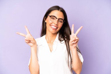 İspanyol güzel kadın gülümsüyor ve mutlu görünüyor, arkadaş canlısı ve tatmin olmuş, zafer ya da barış işareti yapıyor.