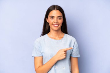 İspanyol güzel kadın neşeyle gülümsüyor, mutlu hissediyor ve yan ve yukarı doğru işaret ediyor, kopya uzayda nesne gösteriyor