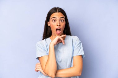 İspanyol güzel kadın şok ve inançsızlık içinde ağzı açık, elleri yanağında ve kolları çaprazlanmış, sersemlemiş ve şaşırmış hissediyor