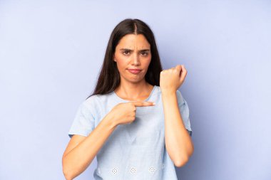 İspanyol güzel kadın sabırsız ve kızgın görünüyor, saati gösteriyor, dakiklik istiyor, zamanında gelmek istiyor.