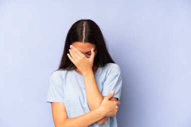 İspanyol güzel kadın stresli, utanmış ya da üzgün görünüyor, baş ağrısı var, yüzünü eliyle kapatıyor.