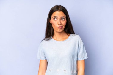 İspanyol güzel kadın şaşkın ve şaşkın görünüyor, merak ediyor veya bir sorunu çözmeye çalışıyor ya da düşünüyor.