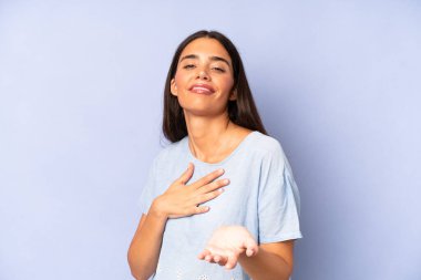 İspanyol güzel kadın mutlu ve aşık, bir eli kalbinin yanında, diğer eli önde uzanmış, gülümsüyor.