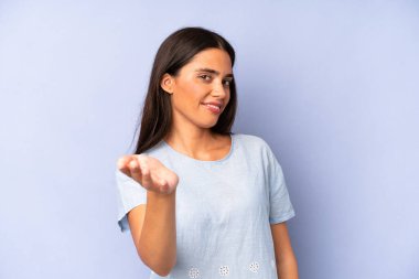 İspanyol güzel kadın gülümsüyor, mutlu görünüyor, kendinden emin ve arkadaş canlısı, bir anlaşmaya varmak için el sıkışıyor, işbirliği yapıyor.