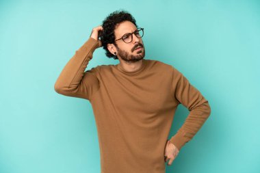 Genç sakallı adam şaşkın ve kafası karışmış hissediyor, başını kaşıyor ve yan tarafa bakıyor.