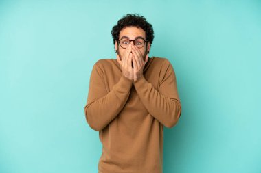 Genç sakallı adam mutlu, neşeli, şanslı ve şaşkın görünüyor. İki eliyle ağzını kapatıyor.