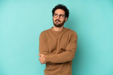 Genç sakallı adam şüphe ediyor ya da düşünüyor, dudağını ısırıyor ve kendini güvensiz ve gergin hissediyor, kenarda yer arıyor.