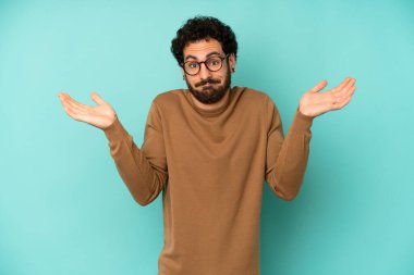 Genç sakallı adam şaşkın ve şaşkın hissediyor, şüpheci, farklı seçenekleri tartıyor veya komik bir ifadeyle seçiyor.