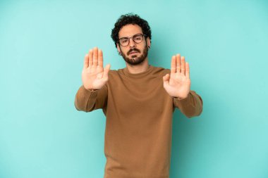 Genç sakallı adam ciddi, mutsuz, kızgın ve hoşnutsuz görünüyor. Girmeyi yasaklıyor ya da her iki avuçta da dur diyor.