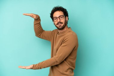 Genç sakallı adam gülümsüyor, mutlu, pozitif ve memnun, fotokopi alanında nesne ya da konsept tutuyor ya da gösteriyor