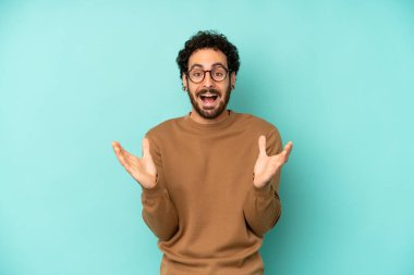 Genç sakallı adam mutlu, heyecanlı, şaşırmış ya da şok olmuş hissediyor. İnanılmaz bir şeye gülümsüyor ve hayrete düşüyor.