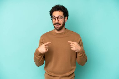 Genç sakallı adam mutlu, şaşırmış ve gururlu hissediyor. Heyecanlı ve şaşkın bir bakışla kendini işaret ediyor.