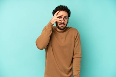 Genç sakallı adam şok olmuş, korkmuş ya da korkmuş görünüyor. Yüzü elle kaplanmış ve parmaklarının arasından gizlice bakıyor.