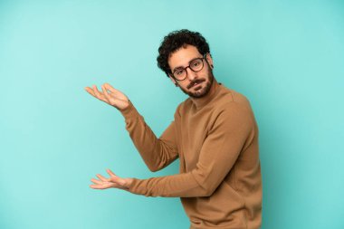 Genç sakallı adam gururla ve güvenle gülümsüyor, mutlu ve tatmin olmuş hissediyor ve fotokopi alanında bir konsept gösteriyor.