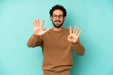 Genç sakallı adam gülümsüyor ve arkadaş canlısı görünüyor. 9 ya da 9 numarayı gösteriyor. Eli önde, geriye doğru sayıyor.