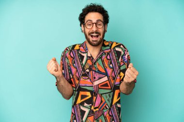 Genç sakallı adam son derece mutlu ve şaşırmış görünüyor, başarıyı kutluyor, bağırıyor ve zıplıyor.