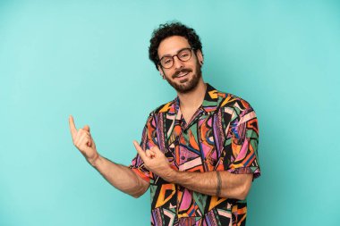 Genç sakallı adam mutlu bir şekilde gülümsüyor ve her iki elinde fotokopi alanında nesne gösteriyor.