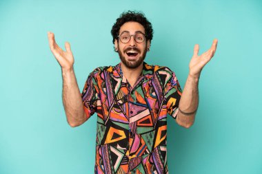 Genç sakallı adam kendini mutlu, şaşkın, şanslı ve şaşırmış hissediyor. Zaferi kutlarken iki elini havaya kaldırıyor.